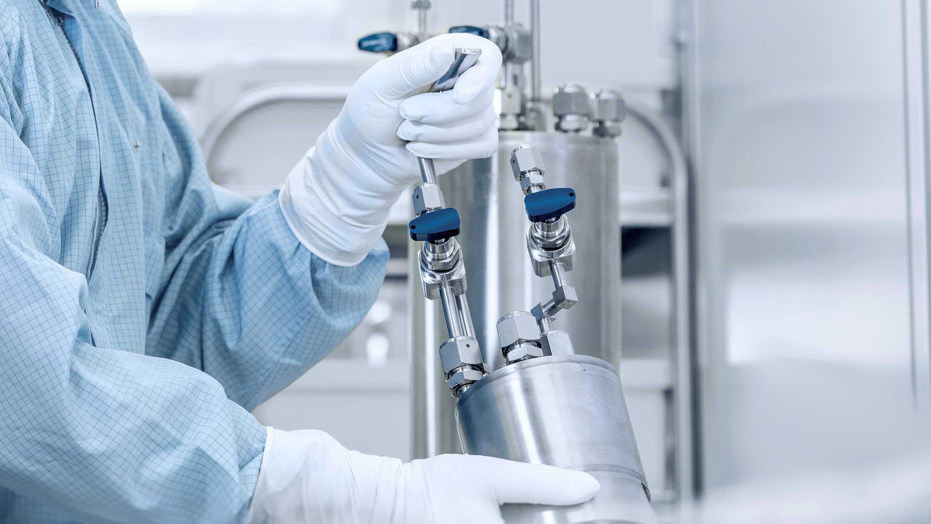 Person in cleanroom clothing holds process vessel in cleanroom environment