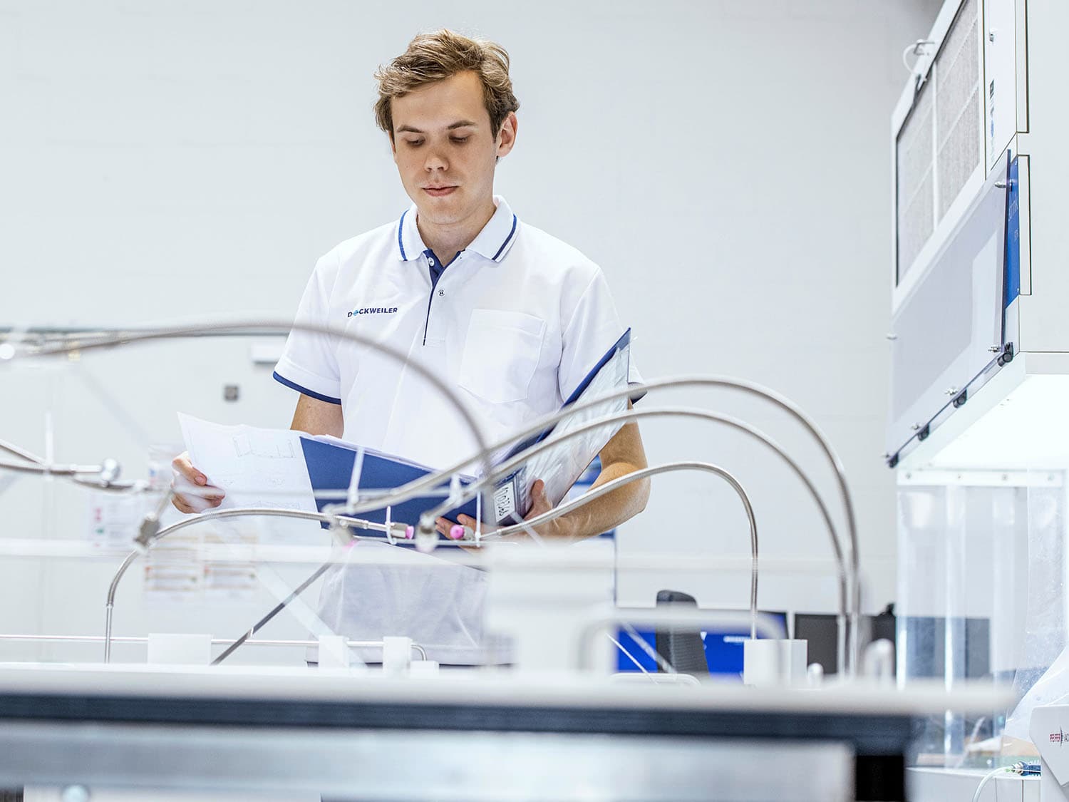 A person in white clothing is inspecting a component