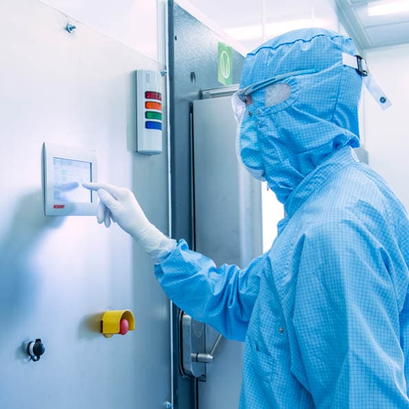 Person in cleanroom clothing uses the control element of the RGA system in the cleanroom