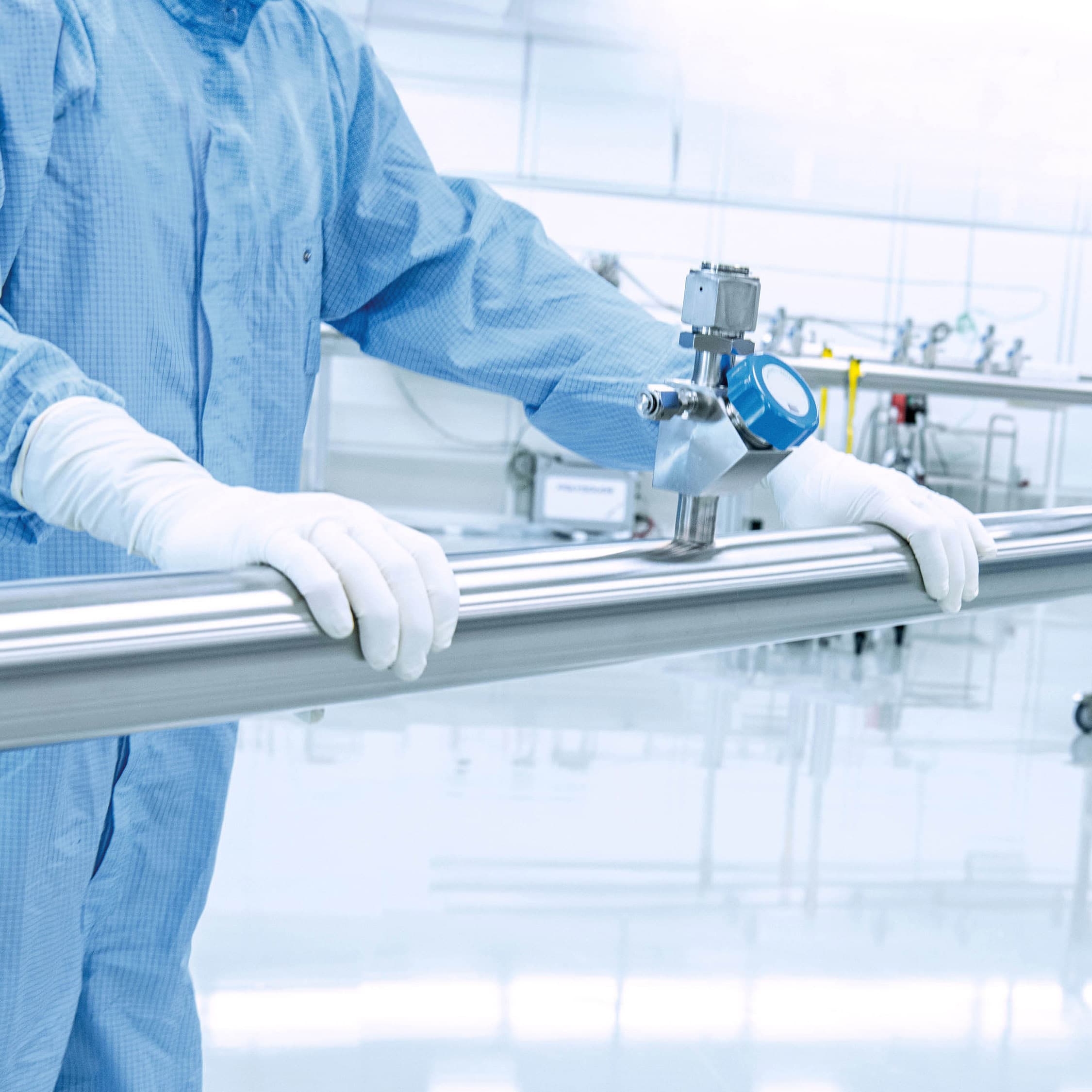 A person works in protective clothing in the clean room and stands next to a manifold with a welded valve .